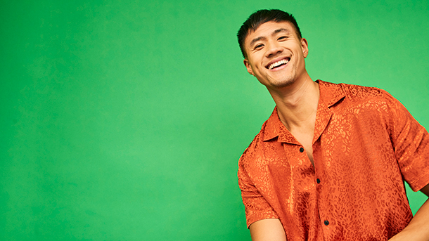Smiling man in orange shirt on a green background
